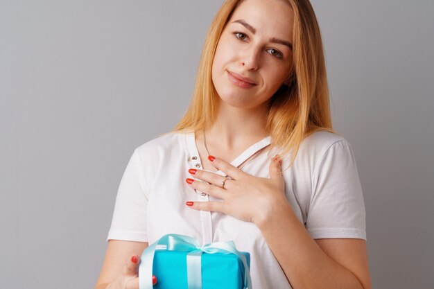 Bonita mujer sosteniendo una caja de regalo azul en sus manos