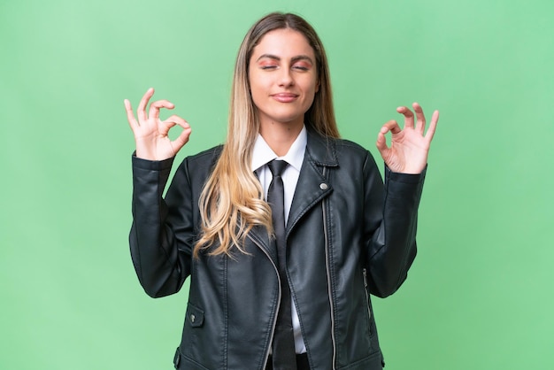 Bonita mujer uruguaya de negocios con una chaqueta de motociclista sobre un fondo aislado en pose zen