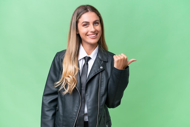 Bonita mujer uruguaya de negocios con una chaqueta de motociclista sobre un fondo aislado que apunta hacia un lado para presentar un producto