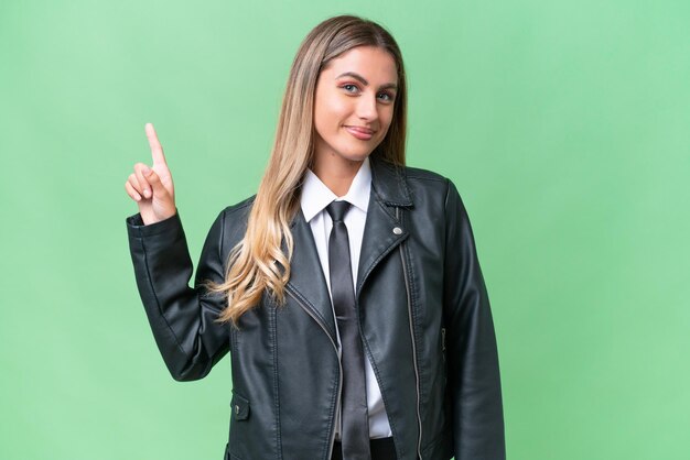 Bonita mujer uruguaya de negocios con una chaqueta de motociclista sobre un fondo aislado que muestra y levanta un dedo en señal de lo mejor