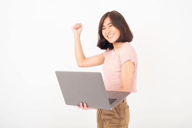 Bonita mulher adolescente asiática está trabalhando com o computador na parede branca