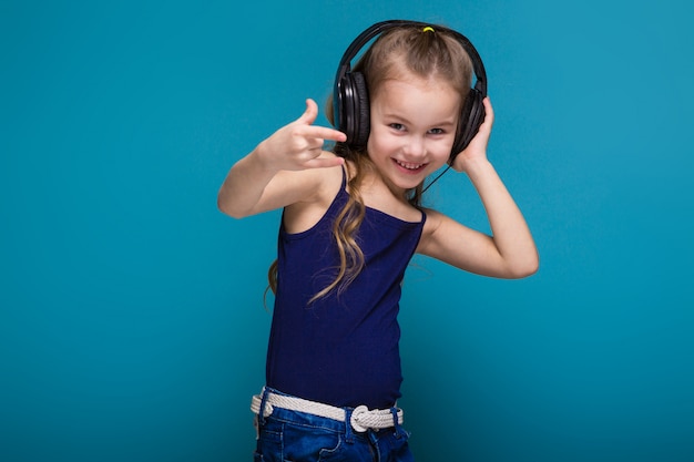 Bonita niña de camisa y auriculares con pelo brunet.