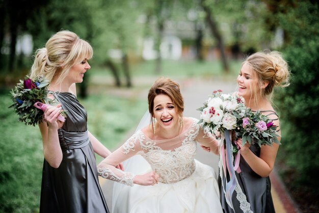 Bonita novia y damas de honor posan en un parque verde