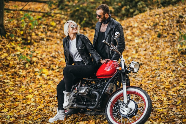 Bonita pareja cerca de moto roja en la carretera en el bosque