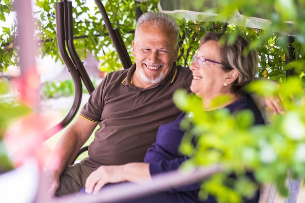Bonita pareja de hermosos ancianos caucásicos de 70 años sentarse al aire libre en casa divirtiéndose con sonrisas y risa. vida feliz juntos para siempre en el amor y disfrutar del tiempo de retiro. centrarse en el hombre