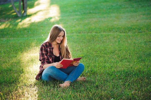 Bonita rubia joven leyendo un libro en el parque