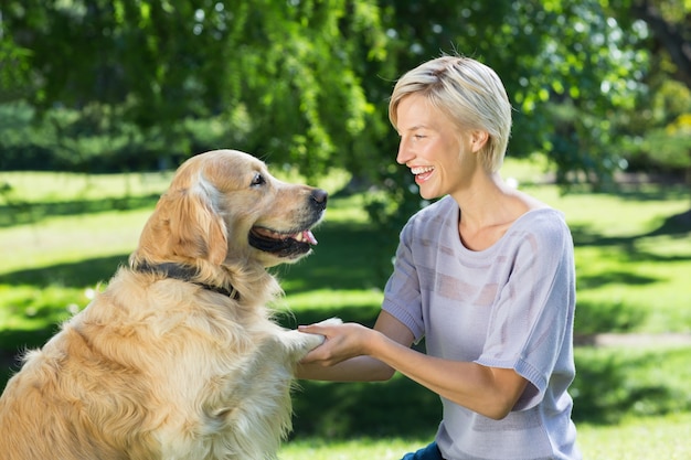 Bonita rubia jugando con su perro en el parque