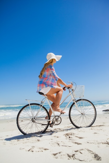 Bonita rubia en un paseo en bicicleta en la playa