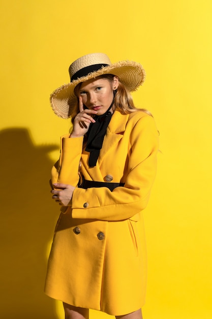 Bonita rubia con pecas en traje amarillo y sombrero de paja en amarillo