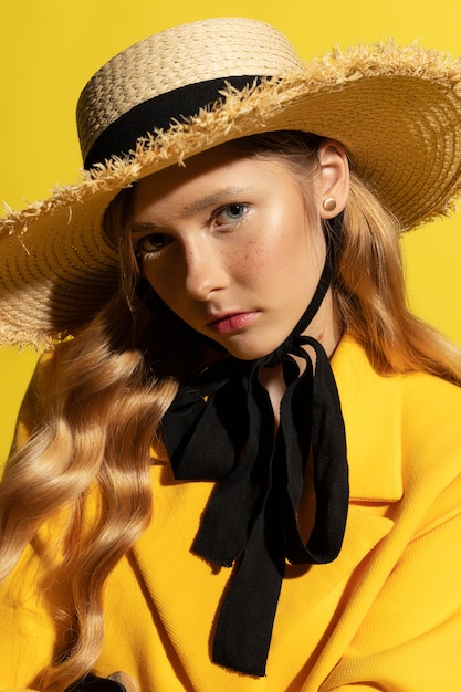 Bonita rubia con pecas en traje amarillo y sombrero de paja en amarillo