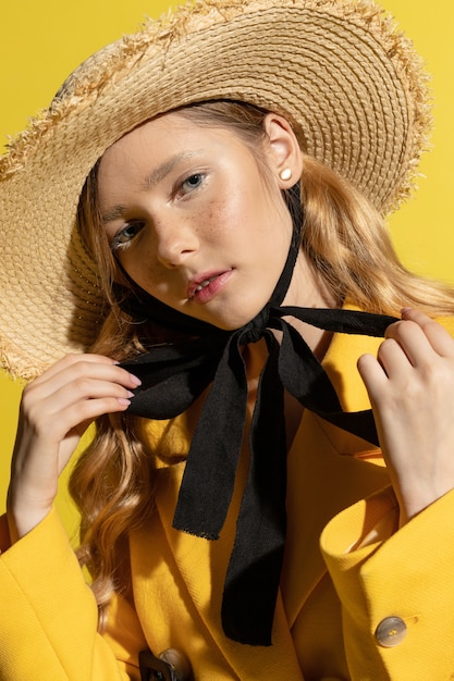 Bonita rubia con pecas en traje amarillo y sombrero de paja en amarillo