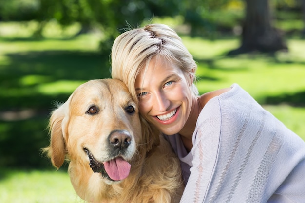 Bonita rubia con su perro en el parque