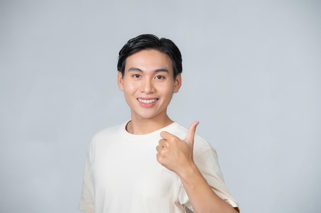 Bonita sonrisa amable hombre asiático en camiseta blanca dando pulgares hacia arriba