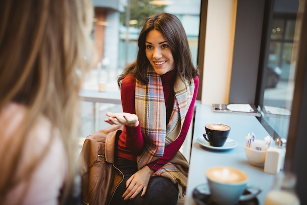 Bonitas amigas charlando tomando un café en la cafetería