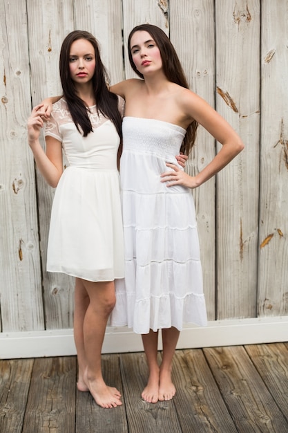 Bonitas amigas posando en vestidos blancos