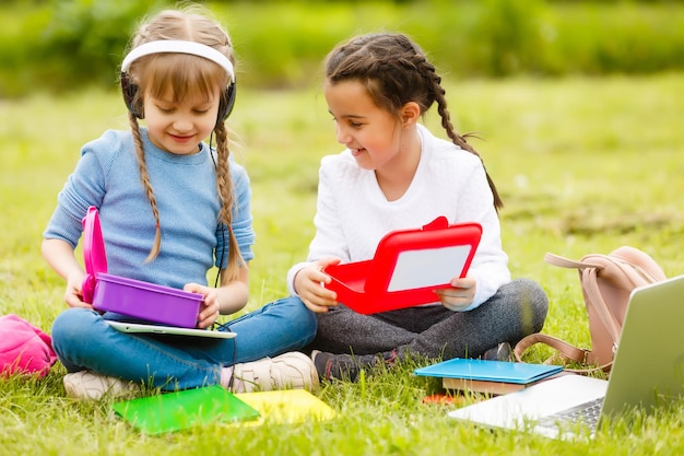 Bonitas colegiais comem ao ar livre. Almoços saudáveis para crianças em idade escolar. Lancheira com frutas. Almoço escolar.