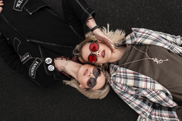 Bonitas lésbicas atraentes em roupas da moda casual e óculos elegantes de juventude descansando na estrada na rua