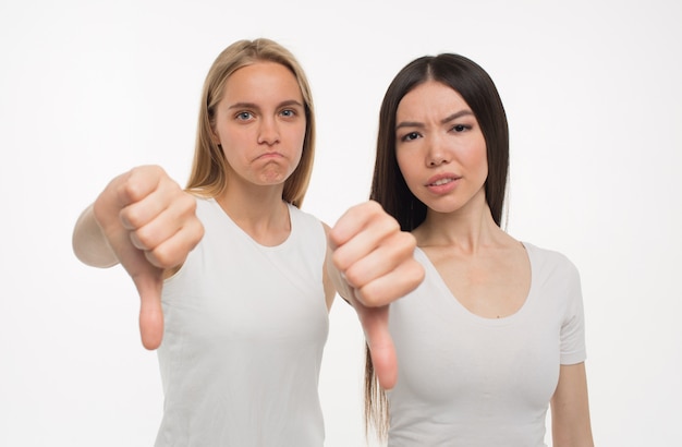 Foto bonitas mujeres jóvenes dan pulgares abajo