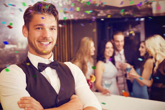 Bonito barman sorrindo para a câmera contra cores voadoras