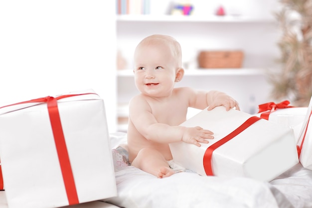 Bonito bebé juega con cajas de regalo sentado en el sofá