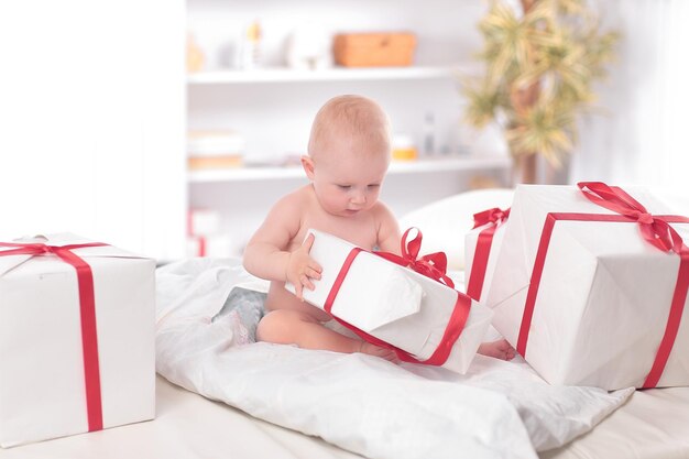 Bonito bebé juega con cajas de regalo sentado en el sofá