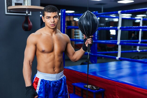 Bonito boxeador masculino parado na academia olhando para a câmera