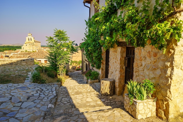 Bonito callejón con antiguas casas de piedra y la iglesia románica al fondo en San Esteban de Gormaz Soria