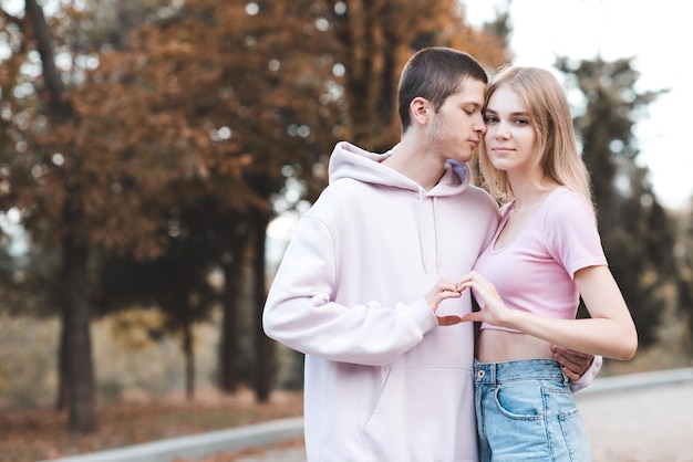 Bonito casal adolescente fazendo formato de coração com as mãos sobre o fundo da natureza do outono Relação de estilo de vida romântico Felicidade