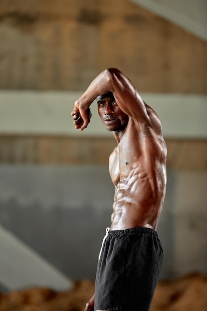 Bonito desportista afro-americano parado na rua enquanto faz uma pausa após o treino Homem negro descansando após o treino