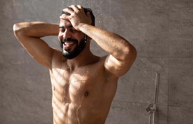 Foto bonito e feliz jovem modelo masculino árabe desfrutando de um banho quente