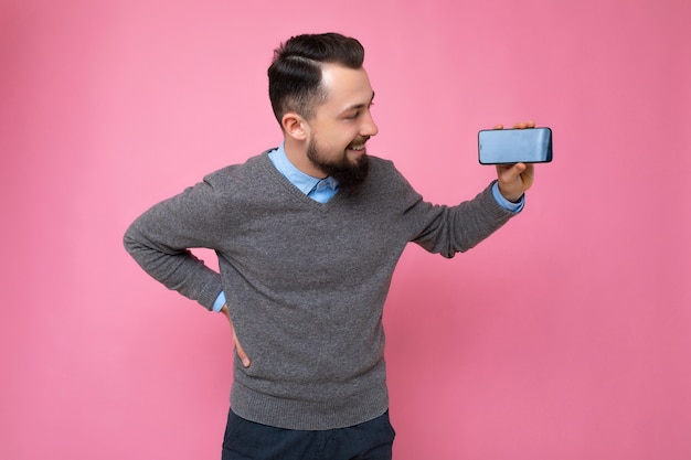 Bonito e feliz jovem morena com barba por fazer com barba e suéter cinza elegante e azul