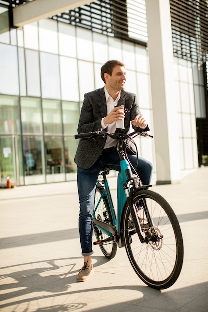 Bonito e jovem empresário na ebike com uma xícara de café para viagem