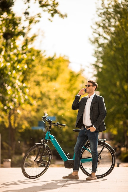 Bonito e jovem empresário na ebike usando o celular