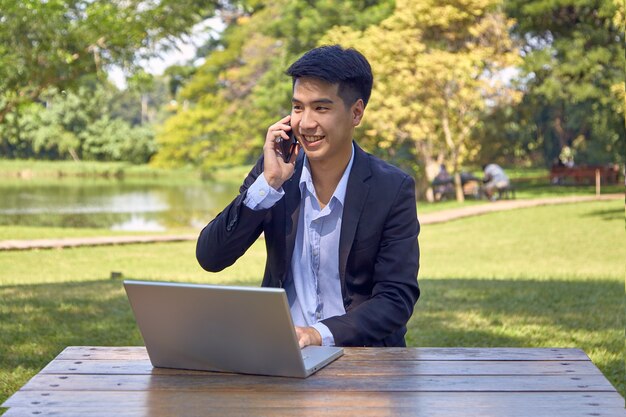 Bonito empresário asiático usando um laptop