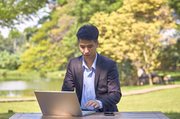 Bonito empresário asiático usando um laptop