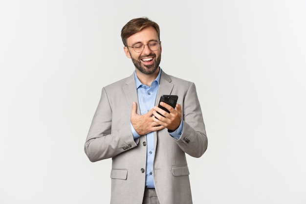 Bonito empresário com barba, usando óculos e terno cinza, rindo de alguma coisa