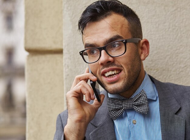 Bonito empresário de terno e óculos falando ao telefone