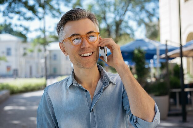 Bonito empresário sorridente usando smartphone