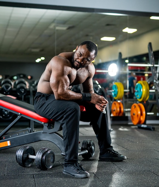 Bonito fisiculturista muscular descansa depois de treinar Homem forte sem camisa descansando após um treino ativo