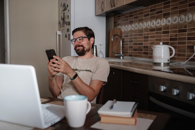 Bonito freelancer sorridente trabalhando remotamente em casa Ele está falando ao telefone