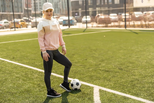 Bonito fútbol femenino. mujer joven en ropa deportiva con una pelota de en el césped. | Foto Premium