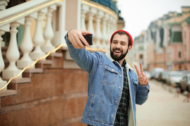 Bonito hipster moderno tomando selfie ao ar livre