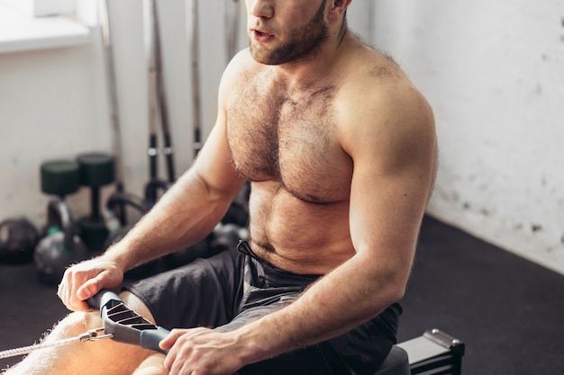 Bonito hombre cansado después de levantar pesas en el gimnasio