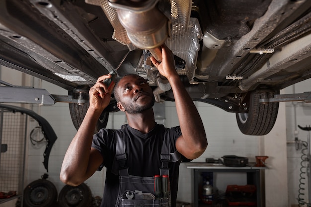 Bonito homem africano reparando fundo do carro