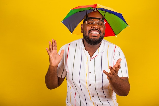 Bonito homem afro brasileiro vestido para carnaval festa típica brasileira folia de carnaval festejando com braços abertos e mãos felizes surpresos