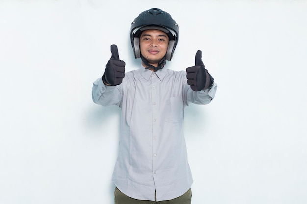 Bonito homem asiático com um capacete de motocicleta mostrando um gesto de ok com o polegar para cima no fundo branco