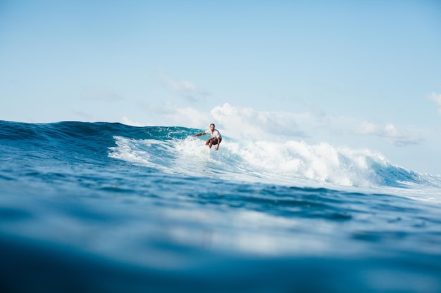 Bonito homem atlético surfando na onda do mar