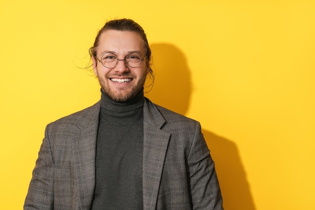 Bonito homem barbudo de óculos sorrindo em fundo amarelo