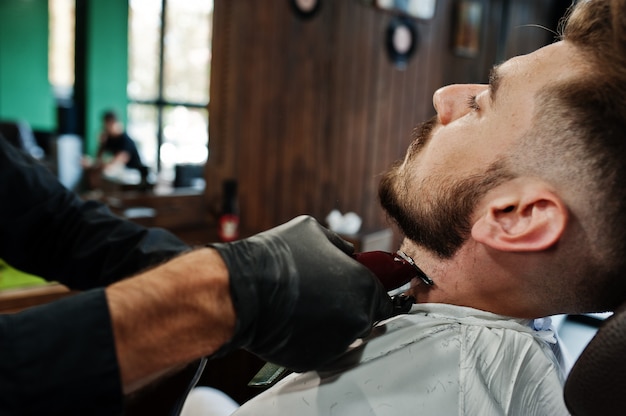 Bonito homem barbudo na barbearia, barbeiro no trabalho.