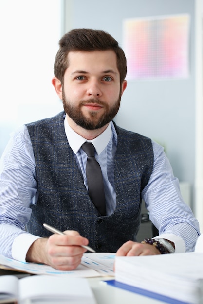 Bonito homem barbudo sorridente no local de trabalho de escritório